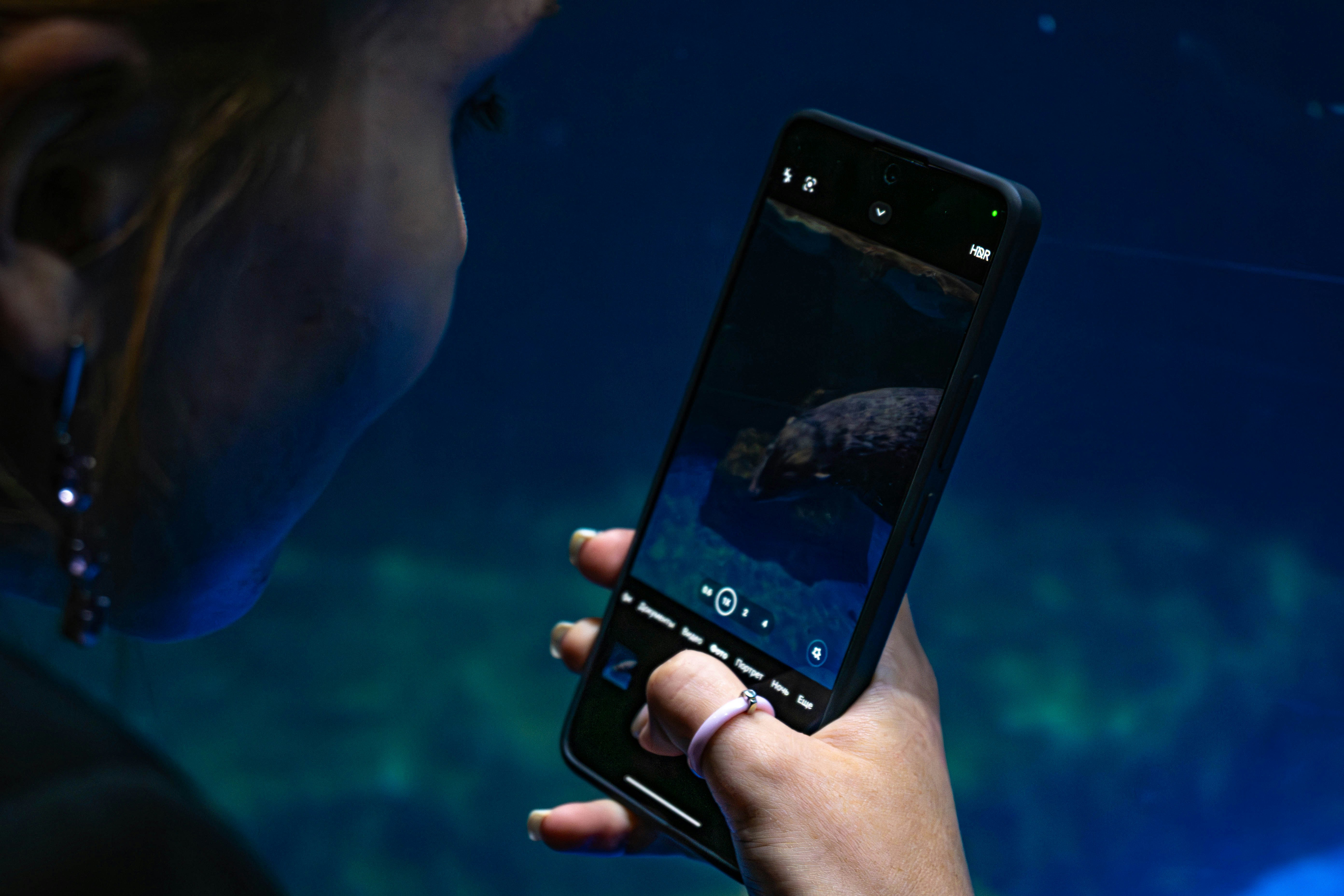 a woman holding a cell phone in front of a fish tank