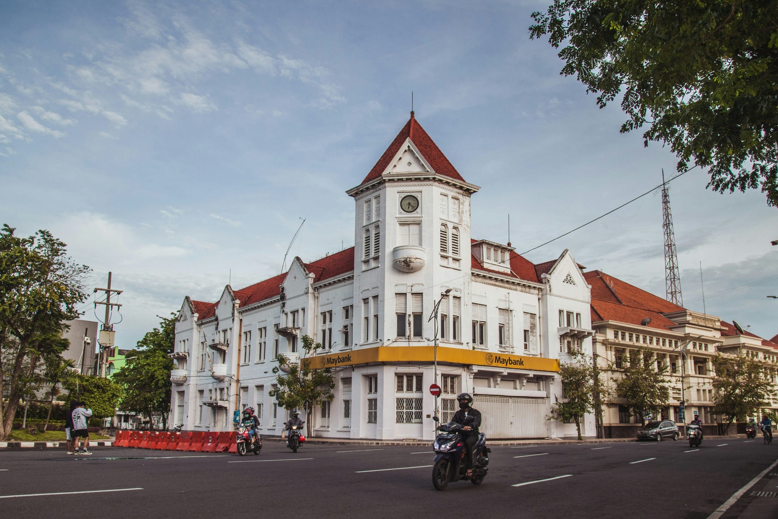 Seorang pria mengendarai sepeda motor di jalan di sebelah gedung-gedung tinggi