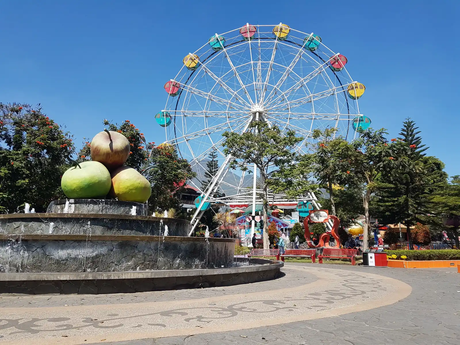 Bianglala warna-warni dan air mancur patung apel di Alun-alun Kota Batu