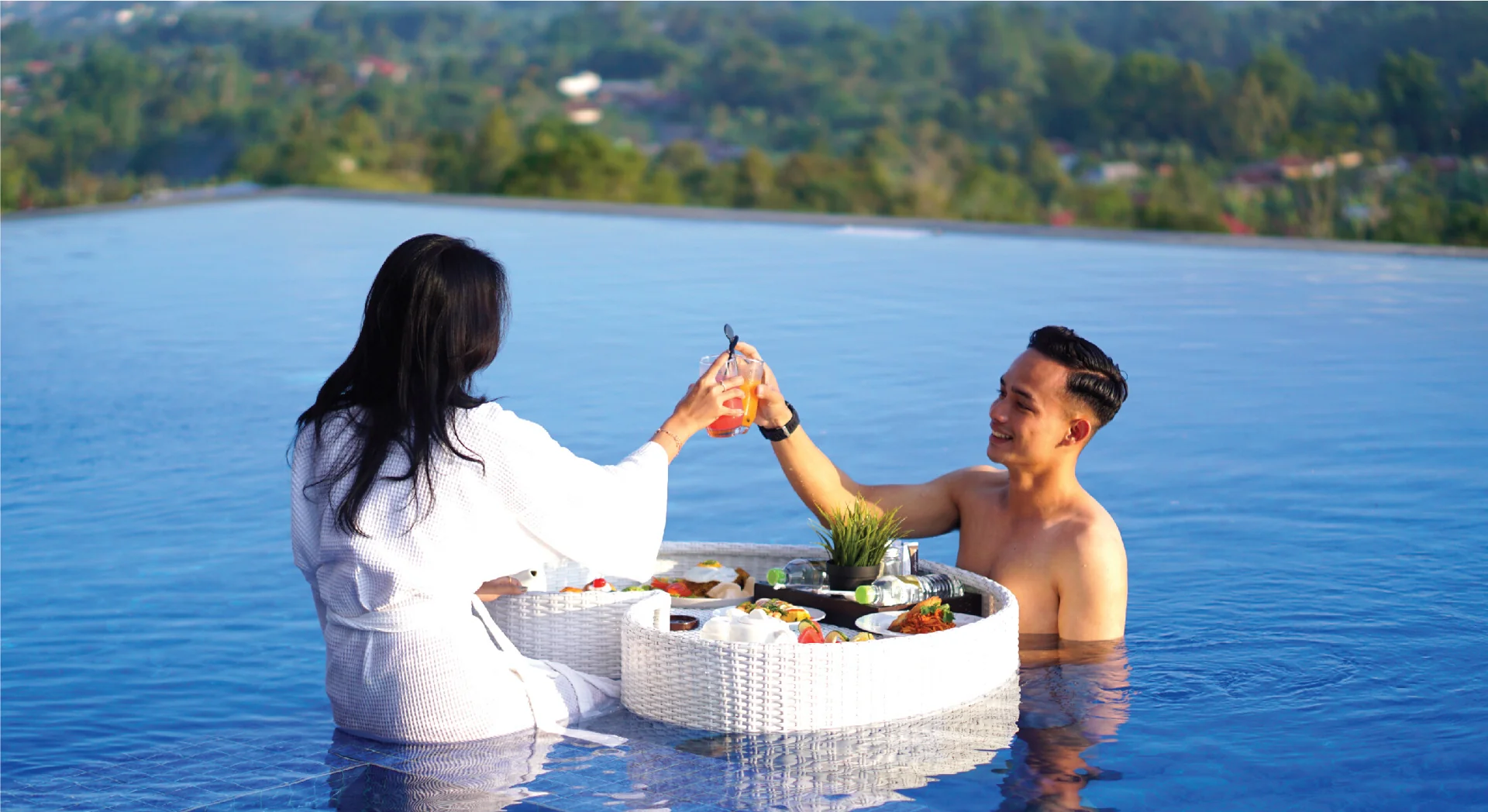 Pasangan bersantai dengan minuman di infinity pool The Balcone Bukittinggi