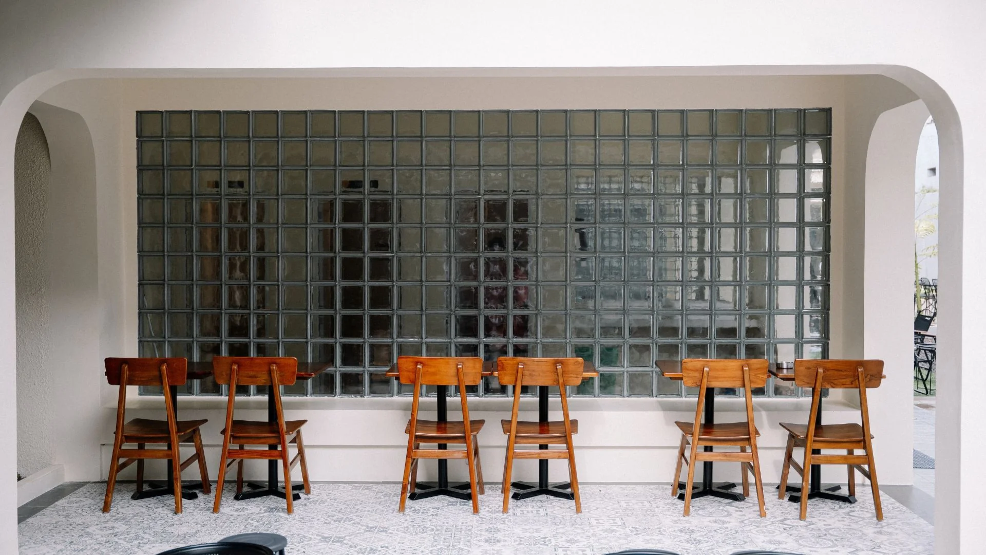 Kursi kayu dan meja bar menghadap dinding glass block di CW Coffee Losari Makassar