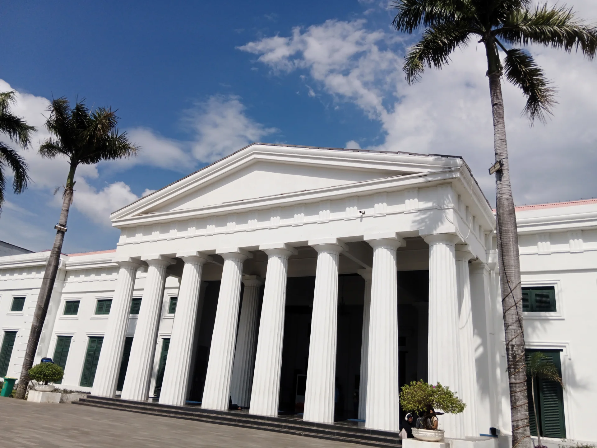 Fasad Museum Seni Rupa dan Keramik dengan deretan tiang putih bergaya neoklasik dan pohon palem di Kota Tua Jakarta