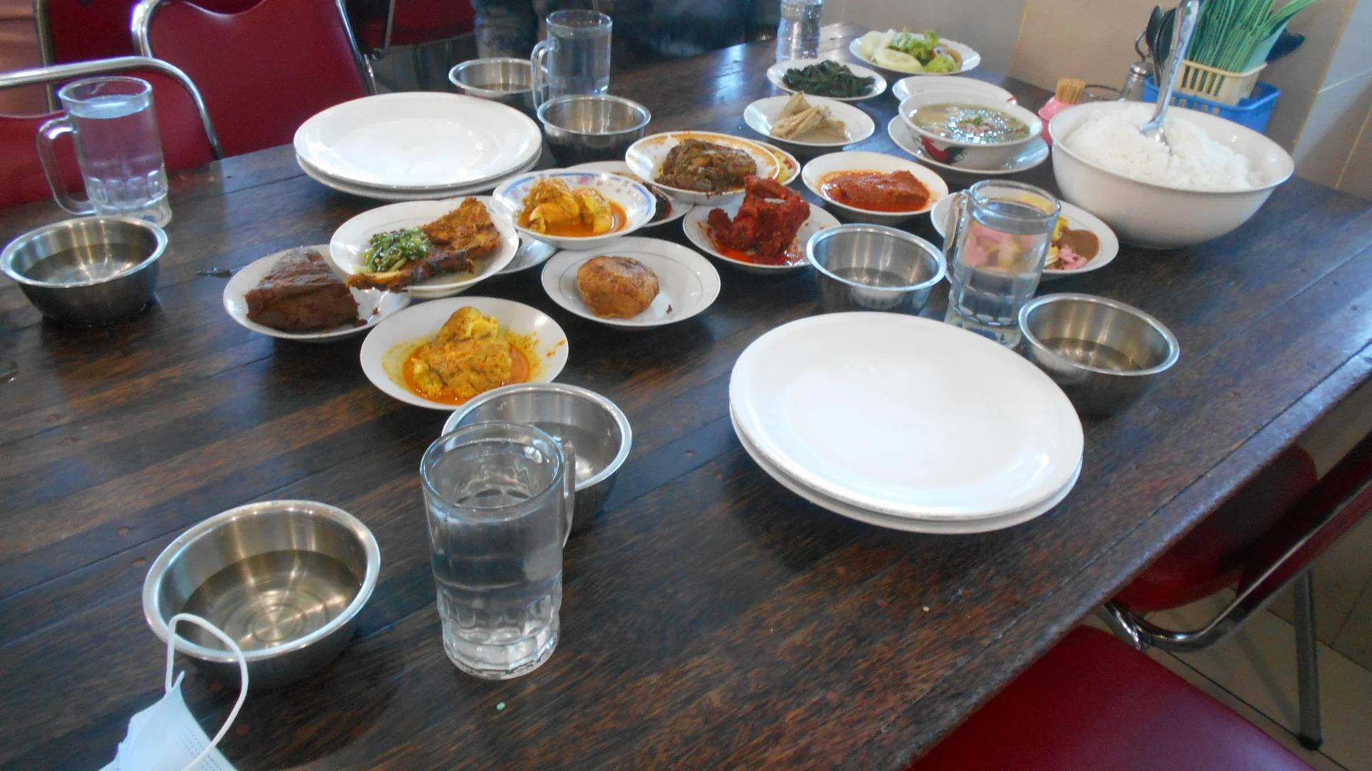 Piring-piring kecil berisi lauk nasi Padang seperti rendang, gulai, dan sambal di meja rumah makan