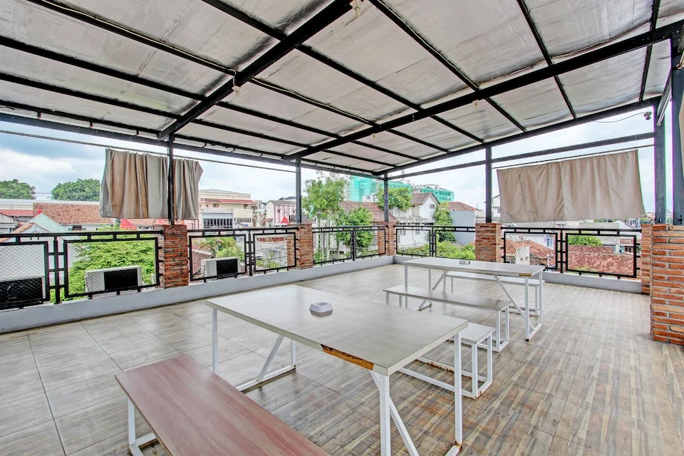 Teras atap Hotel O Penak Malioboro dengan meja dan bangku kayu