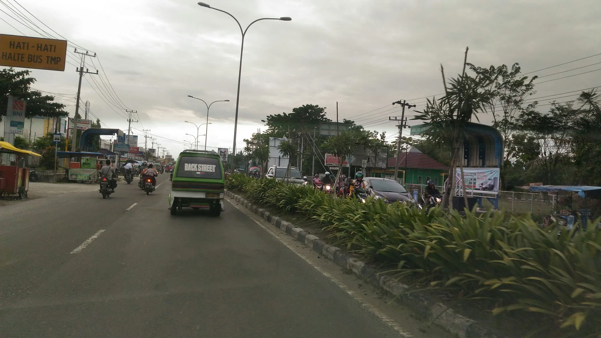 Lalu lintas Jalan HR Soebrantas di kawasan Panam, Pekanbaru, dengan halte bus di tepi jalan