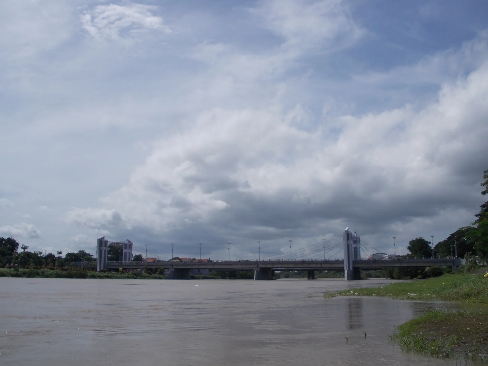 Jembatan Brawijaya melintasi Sungai Brantas di Kota Kediri, dilihat dari tepi sungai saat langit berawan