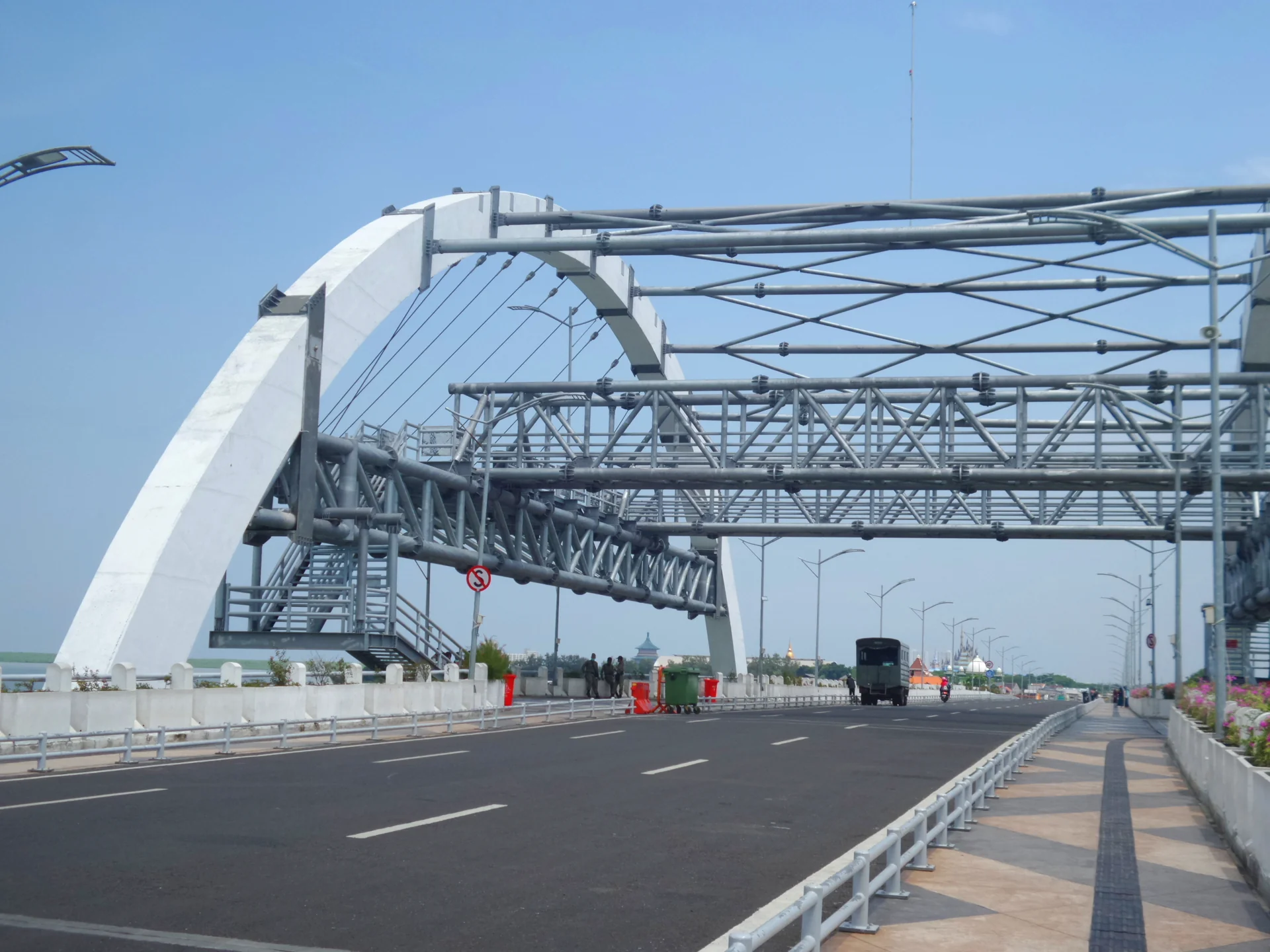 Lengkung putih dan rangka baja Jembatan Suroboyo di pesisir Kenjeran pada siang hari