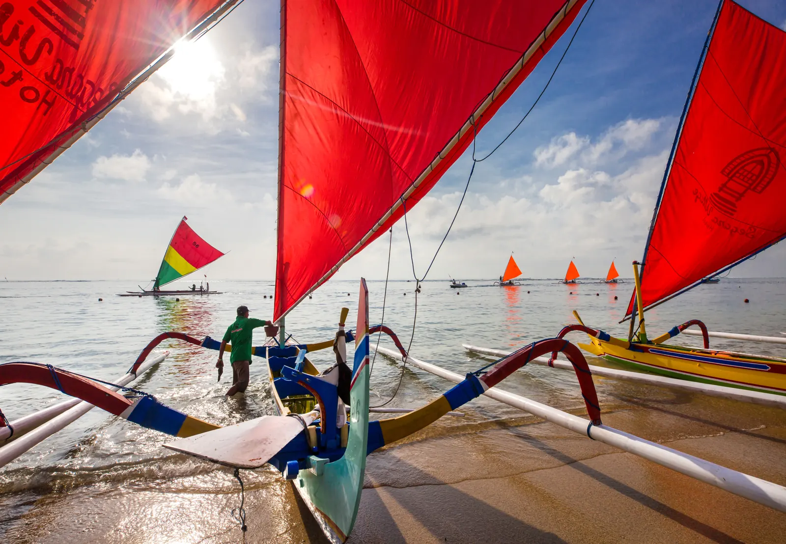 Perahu jukung berlayar merah ditambatkan di tepi Pantai Sanur, Bali dengan laut yang tenang