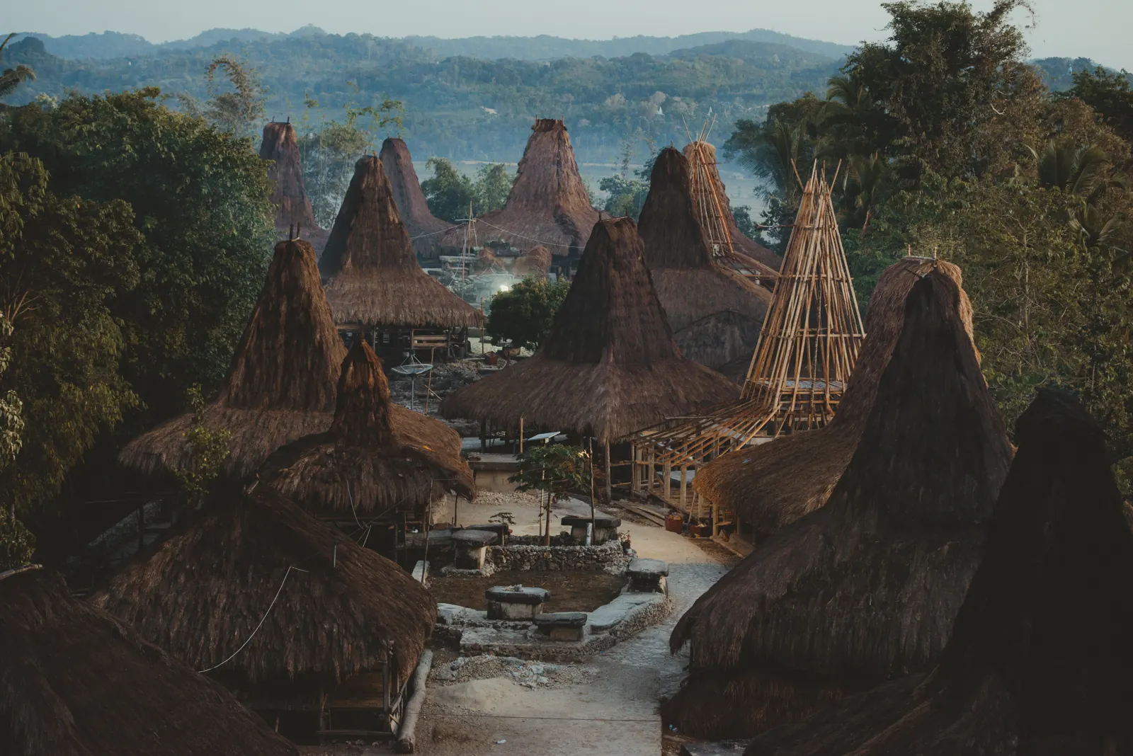 deretan rumah adat beratap ilalang menjulang di Kampung Adat Praijing, Sumba Barat, dengan satu rumah berangka bambu yang sedang dibangun
