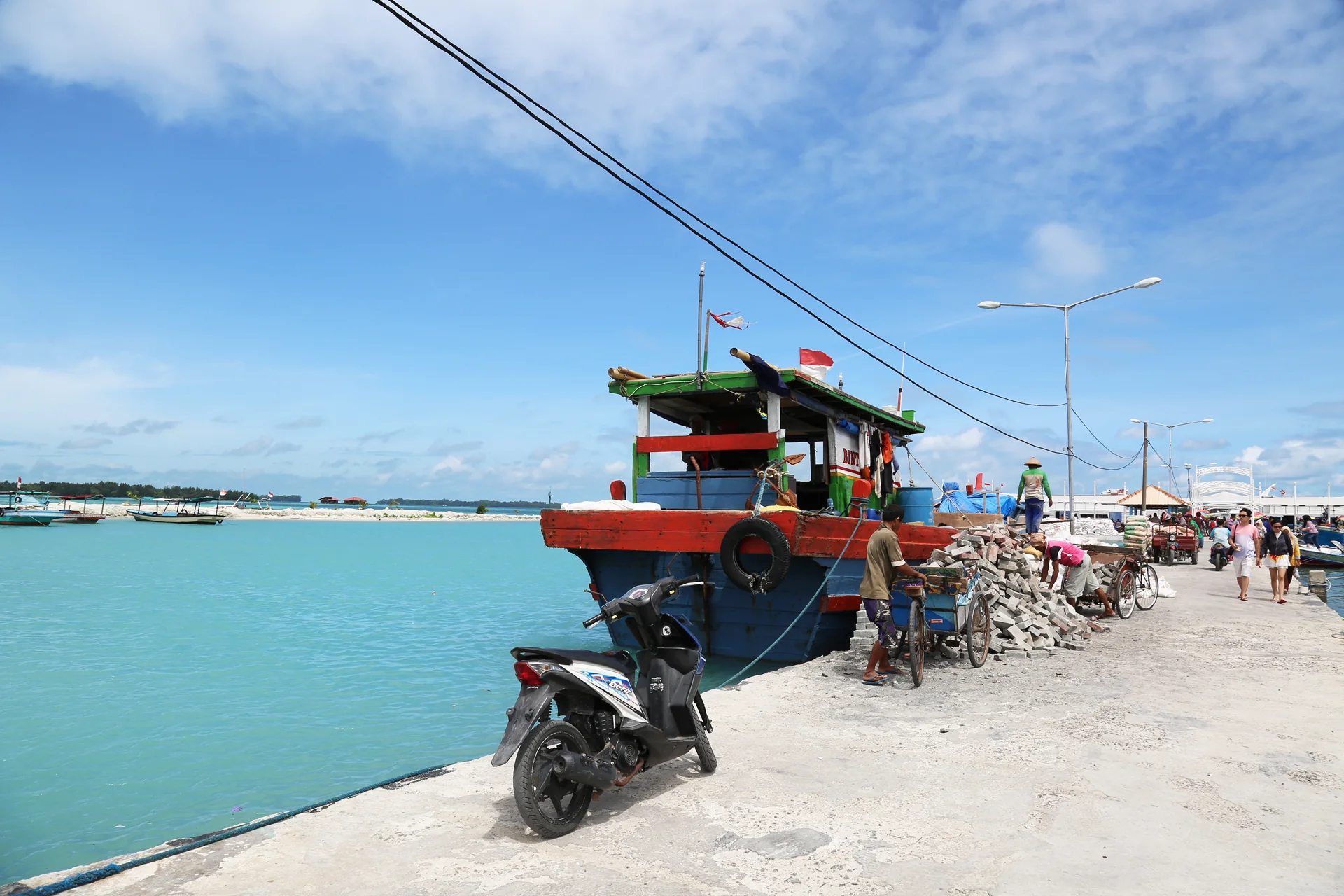 kapal kayu tradisional bersandar di dermaga Pulau Harapan, Kepulauan Seribu, saat warga membongkar muatan batu