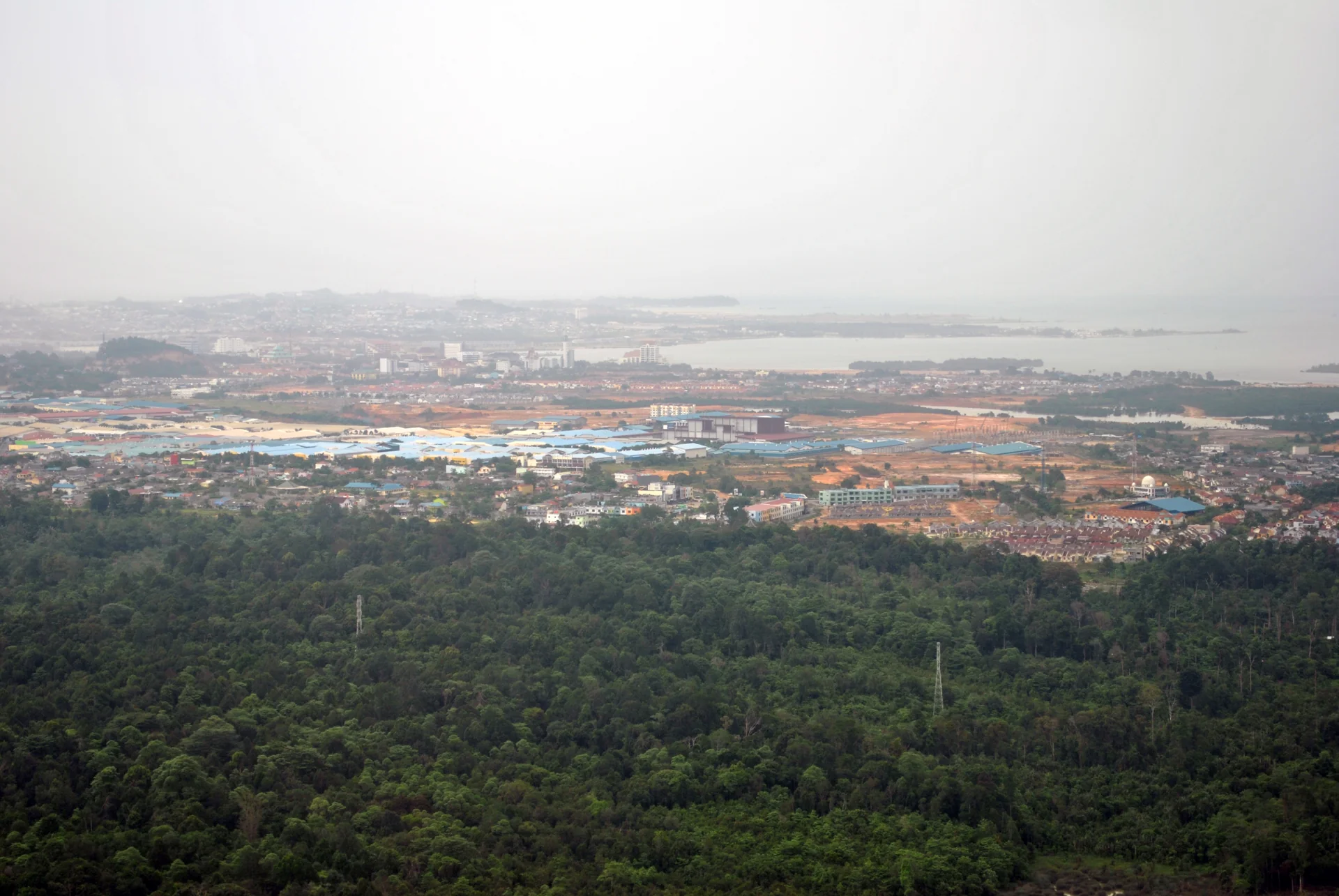 Pemandangan dari ketinggian ke arah kawasan Batam Centre dengan permukiman, atap pabrik, dan teluk