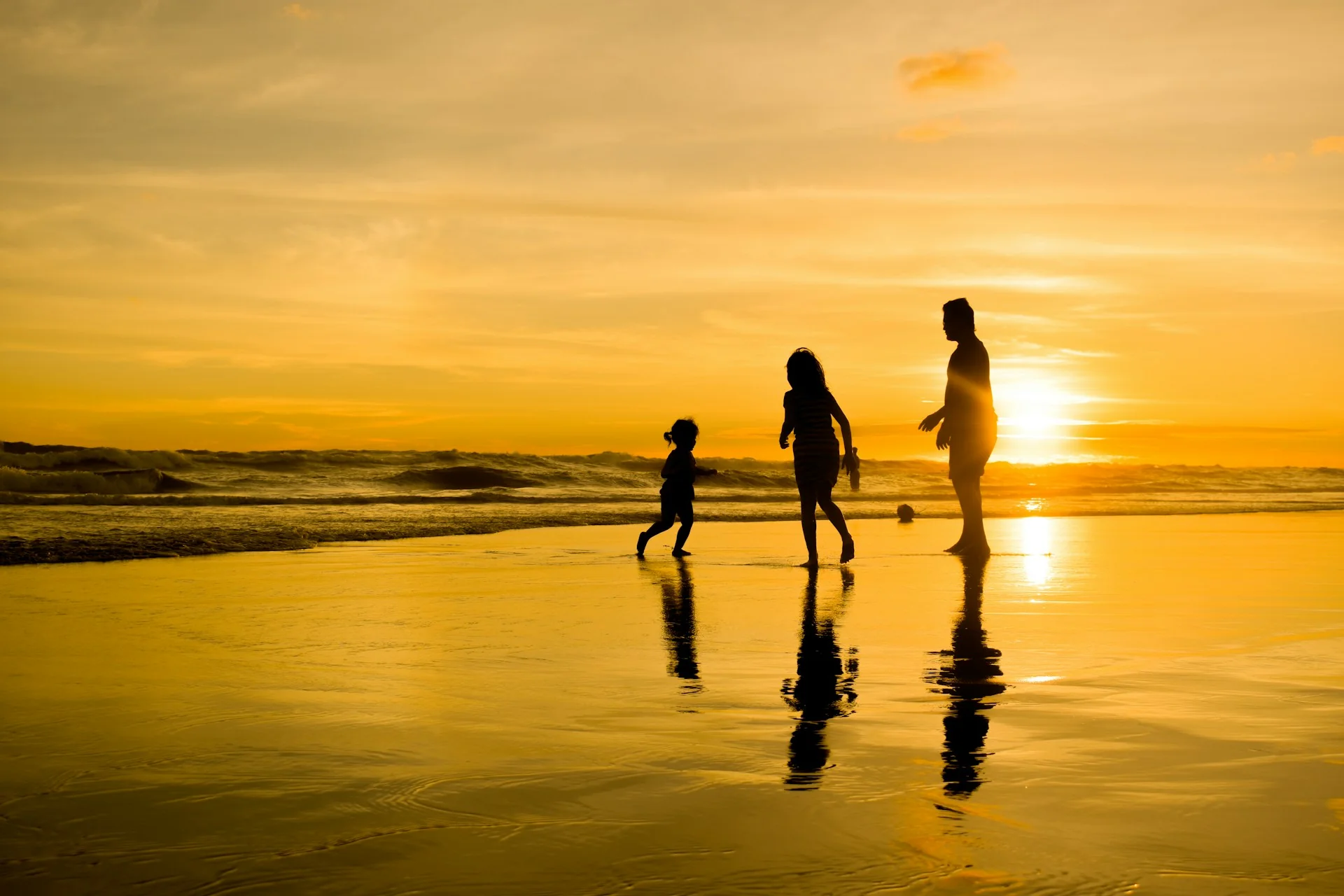 Siluet ayah, ibu, dan anak berjalan di tepi Pantai Parangtritis, Bantul, saat matahari terbenam
