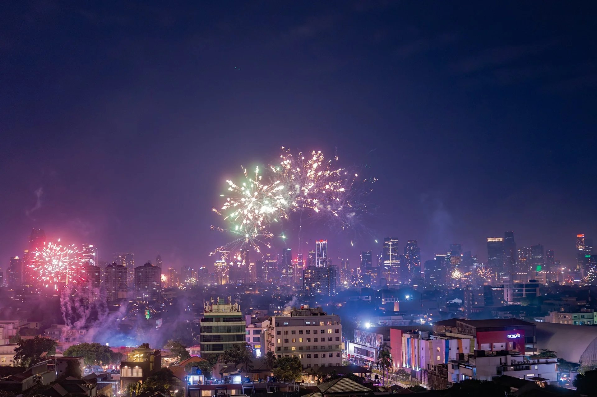 kembang api warna-warni di atas gedung-gedung pencakar langit Jakarta pada malam tahun baru