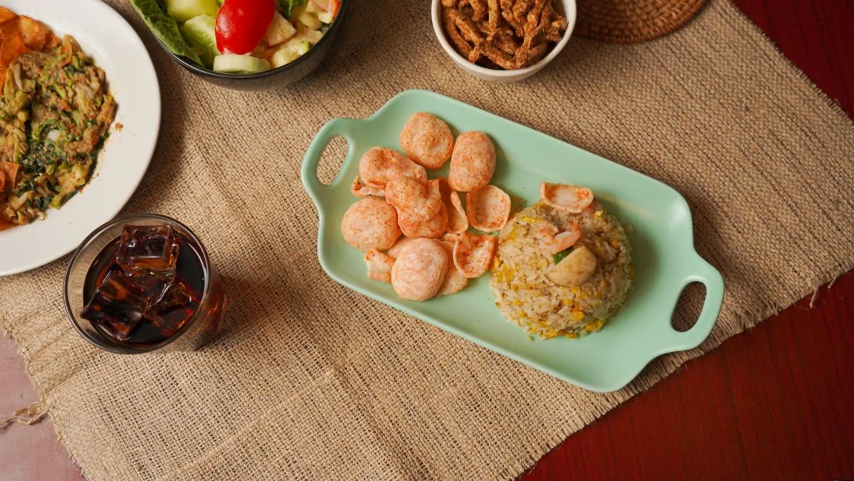 Kerupuk berbumbu pedas Maicih disajikan di piring bersama nasi goreng