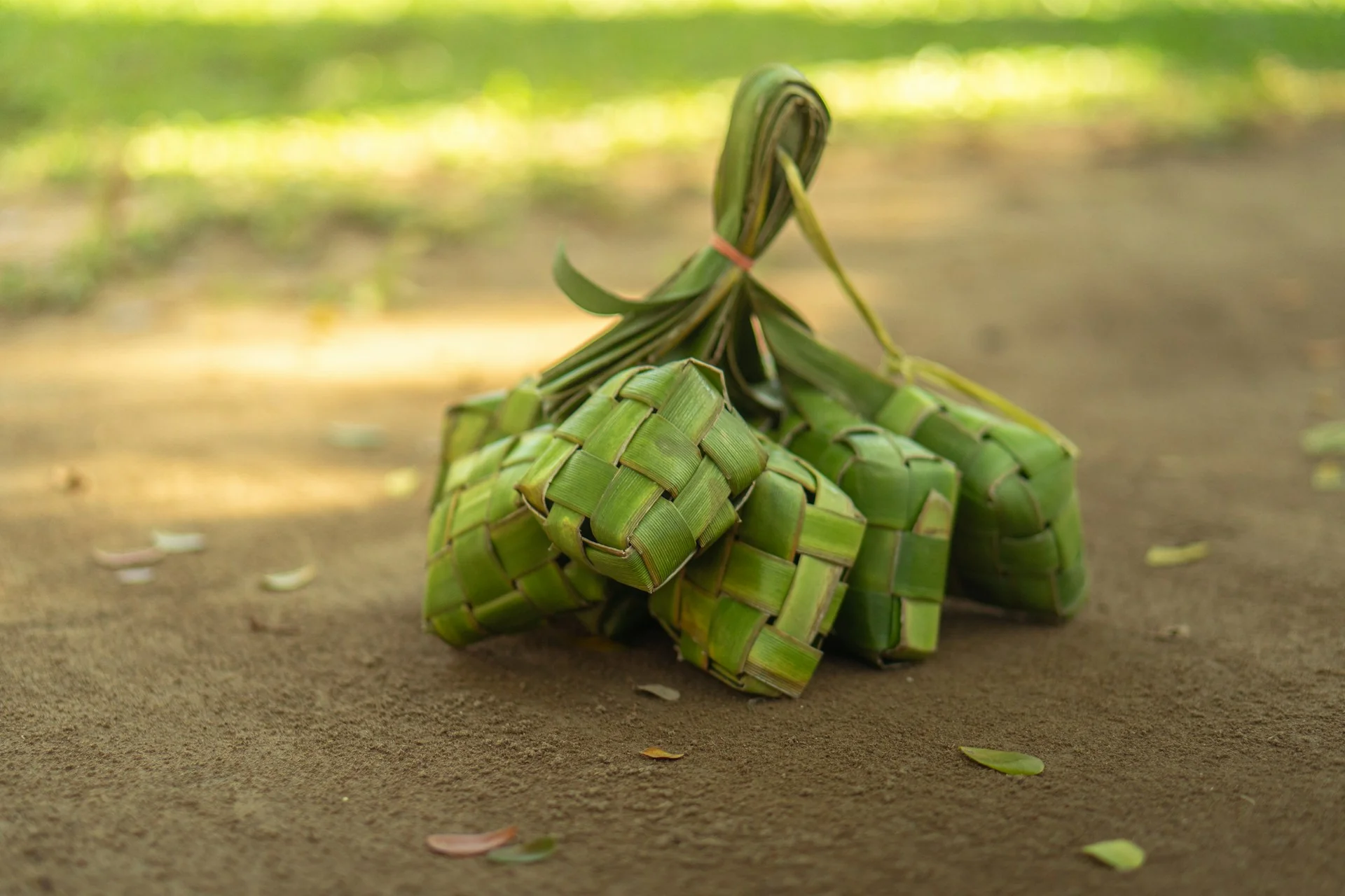 Seikat ketupat dari anyaman janur hijau tergeletak di tanah