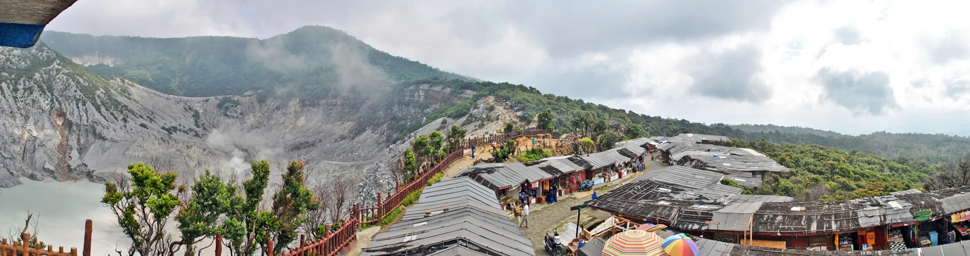 deretan kios suvenir beratap seng di jalur pengunjung tepi Kawah Ratu, Tangkuban Parahu, dengan kawah berasap di sebelah kiri