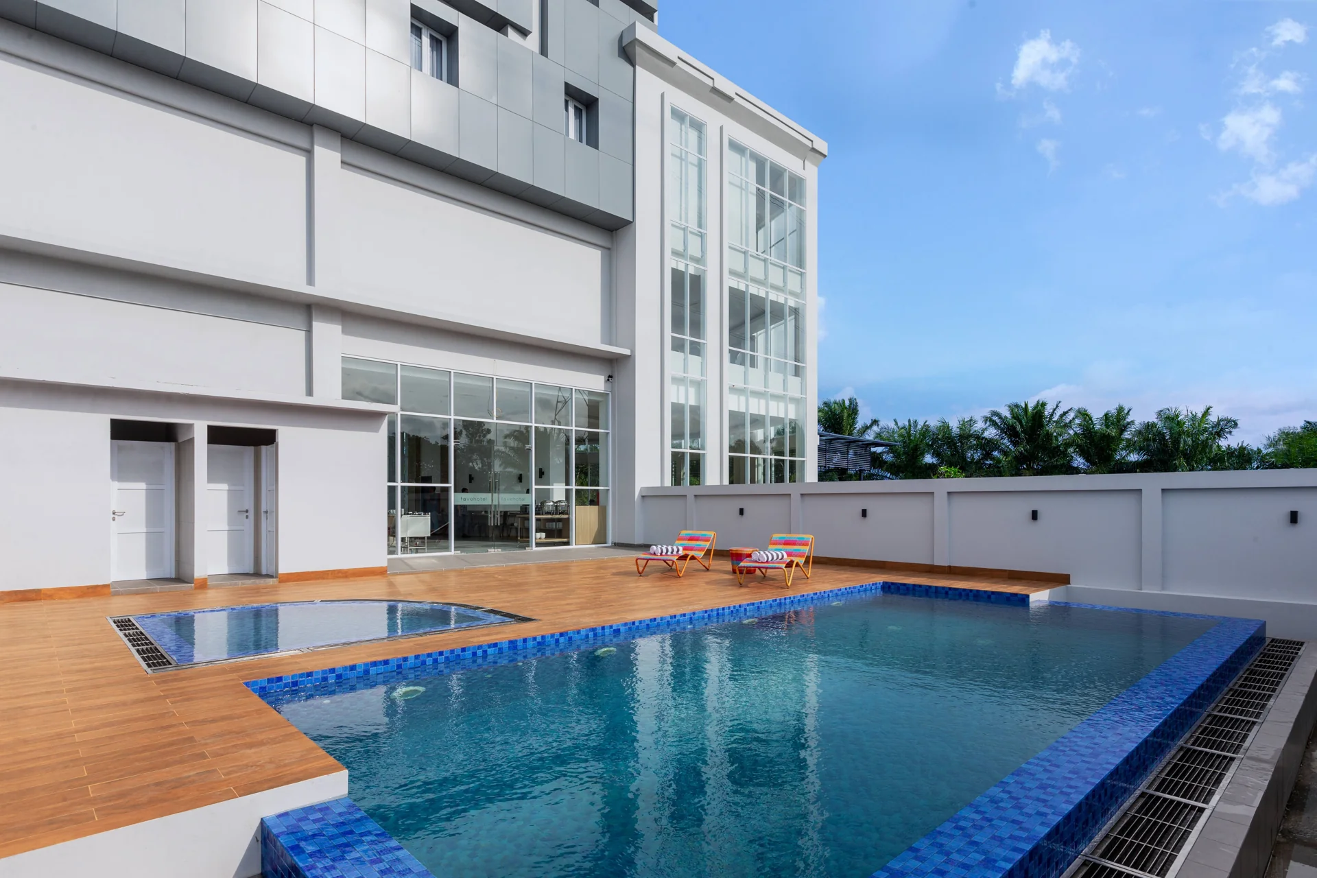 kolam renang favehotel Kediri siang hari dengan dua kursi santai di dek kayu