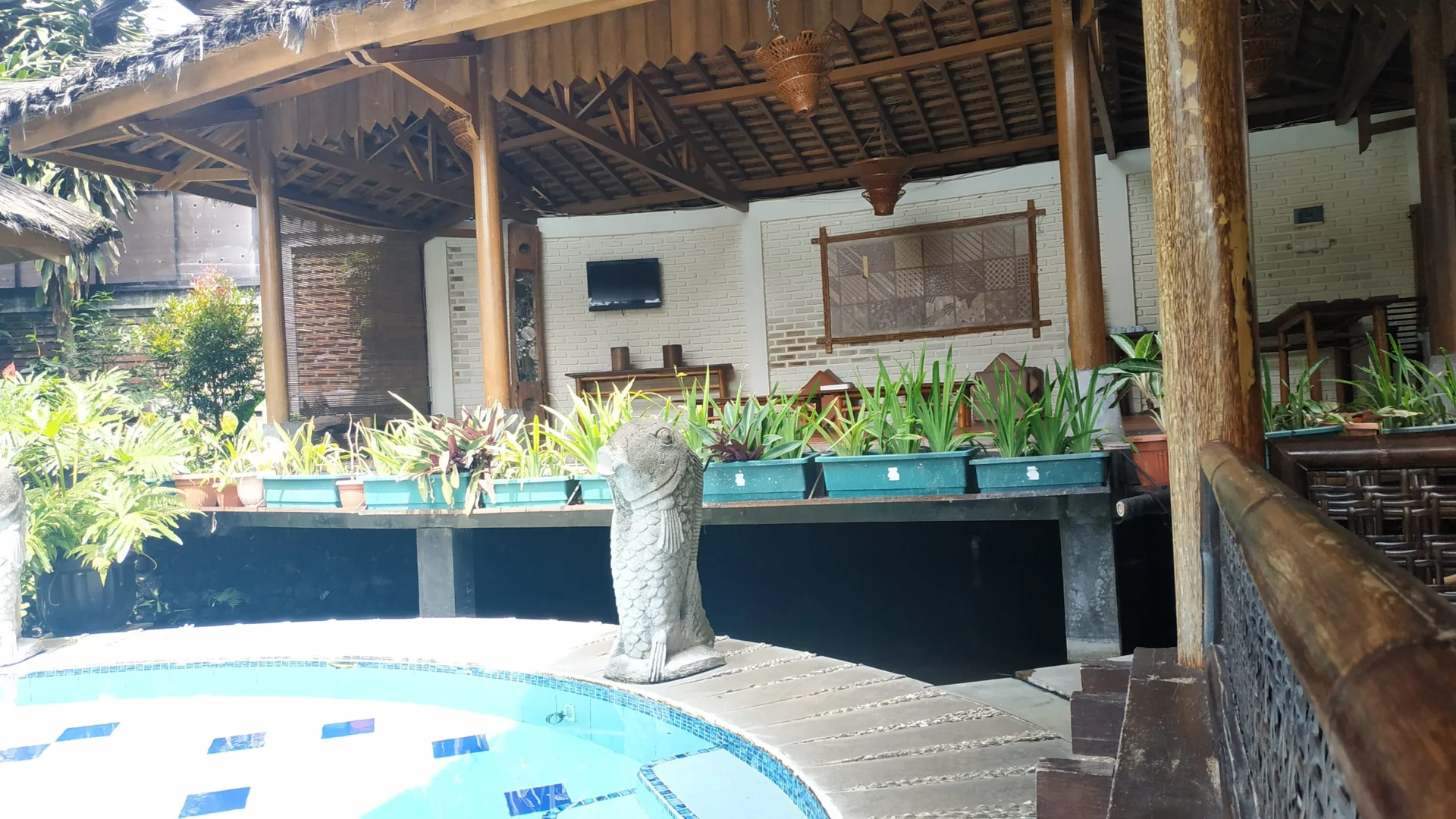 kolam bundar di area Kampung Sumber Alam Resort Garut dengan saung kayu