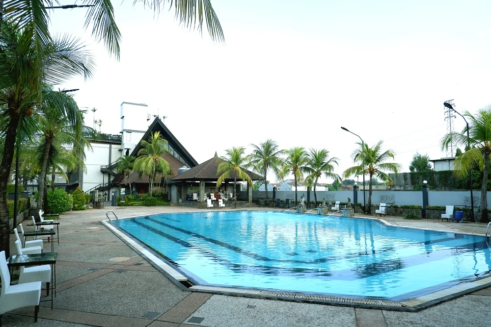 Kolam renang outdoor Hotel Griptha Kudus dengan kursi putih di tepi kolam