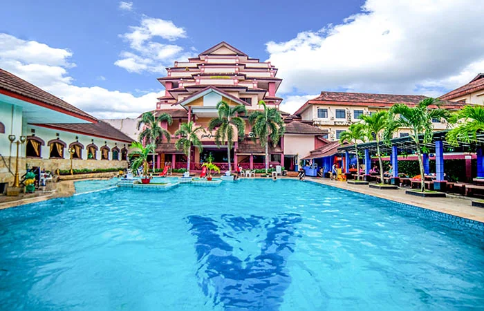 kolam renang outdoor Abadi Hotel & Convention Center Jambi dengan deretan pohon palem