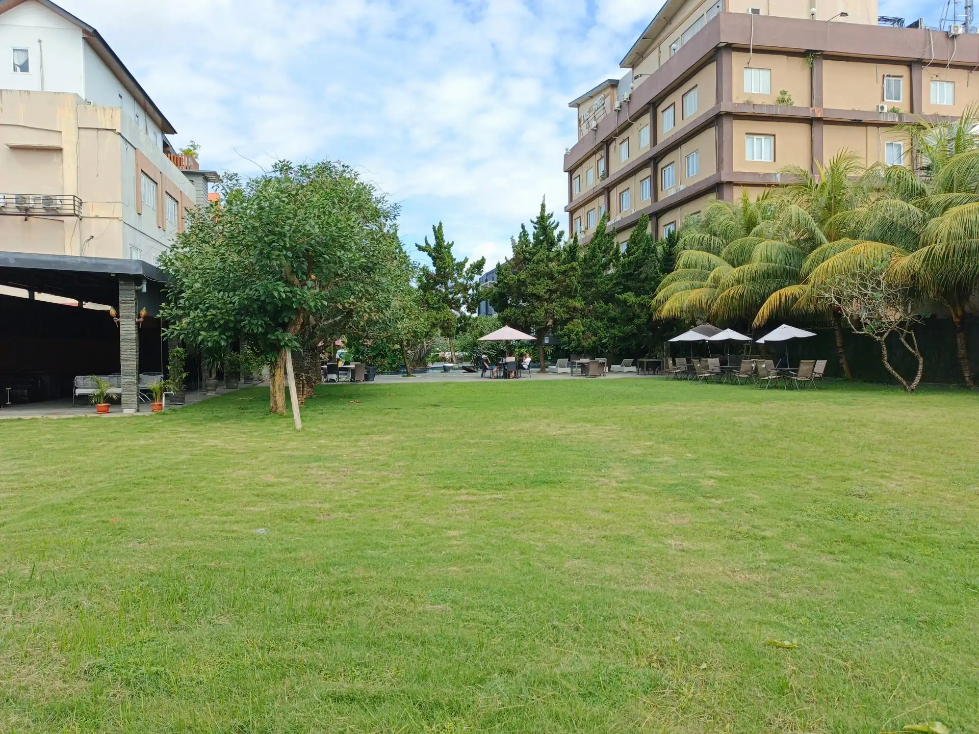 Taman rumput luas di samping area kolam Swiss-Belhotel Kendari