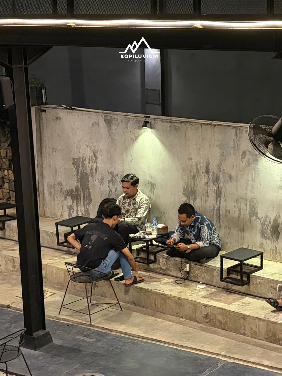 Pengunjung duduk di area beton bergaya industrial Kopiluvium