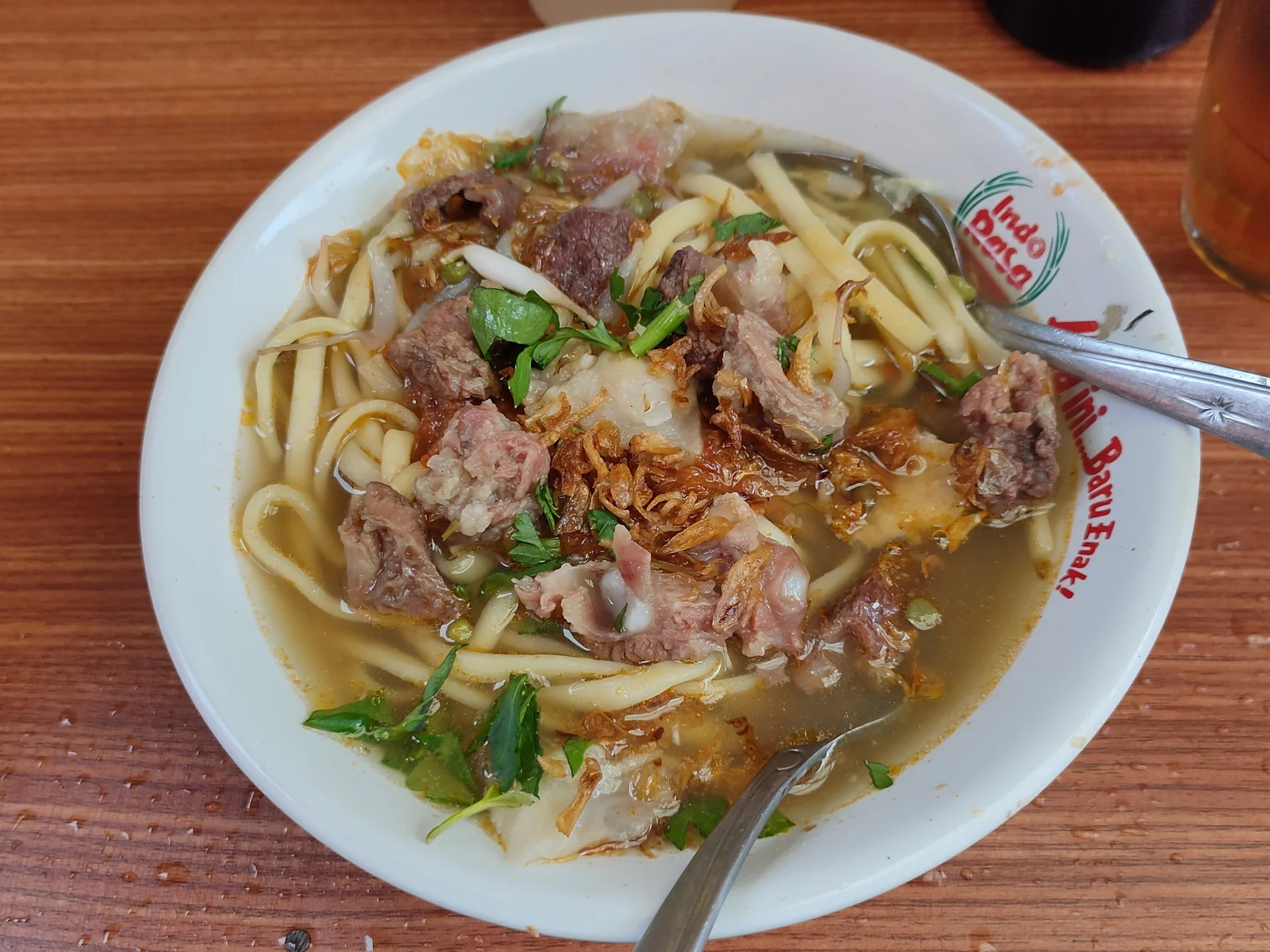 mie kocok varian Sukabumi berisi potongan daging sapi, mi kuning tebal, daun seledri, dan bawang goreng di mangkuk putih
