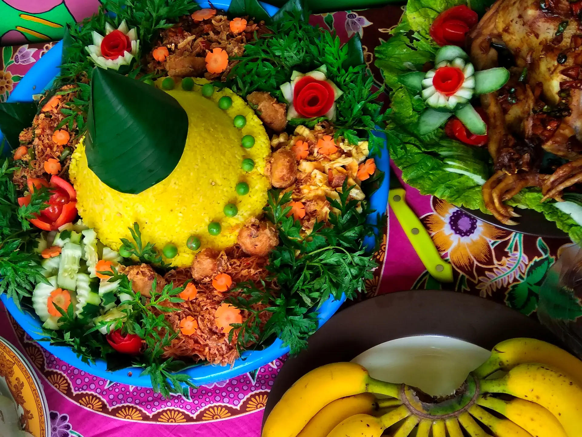 Nasi kuning berbentuk kerucut dikelilingi lauk ayam ungkep, sambal goreng, dan sayur