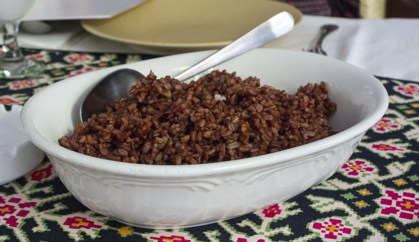 Nasi merah di mangkuk putih oval dengan sendok saji