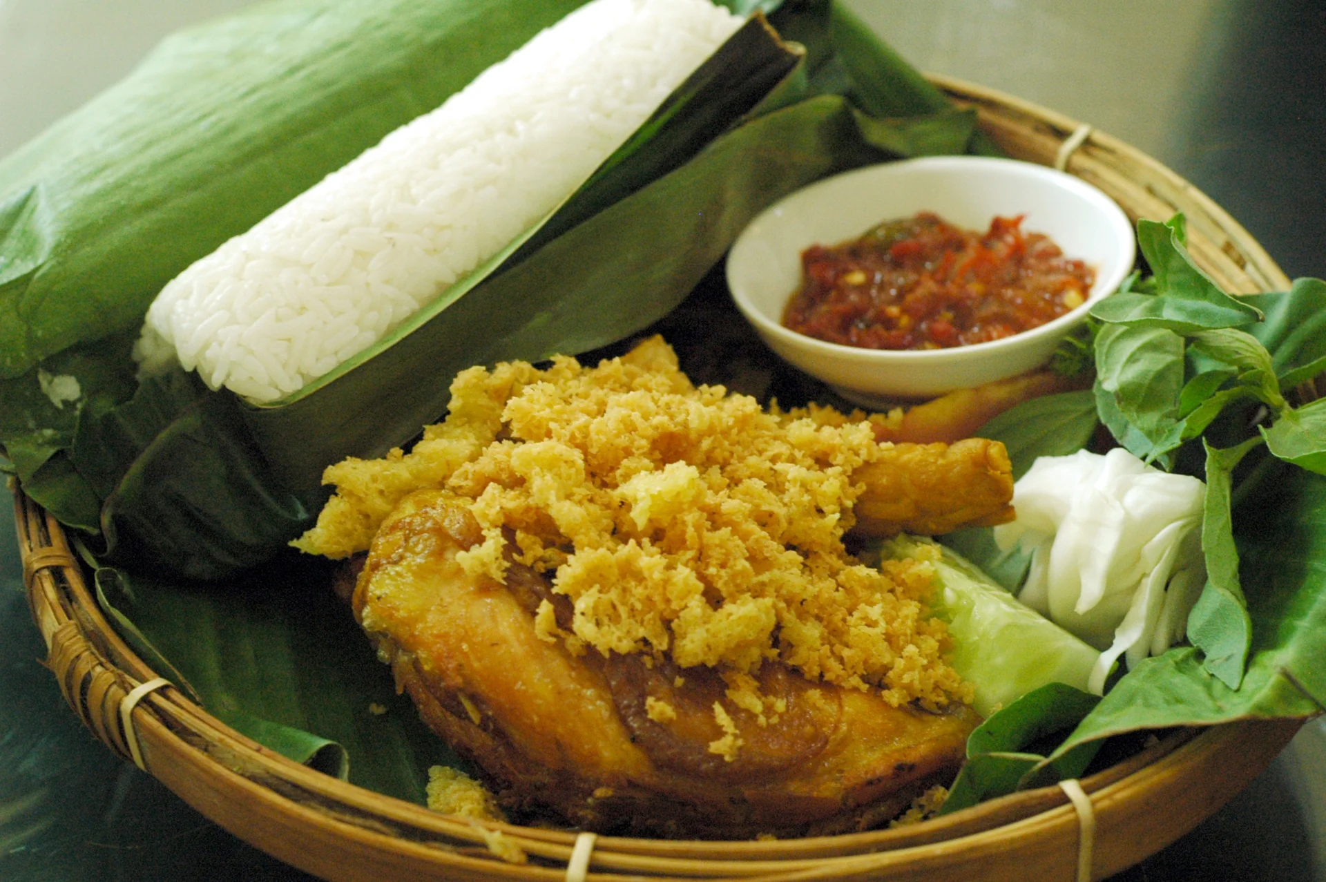 Nasi timbel dibungkus daun pisang dengan ayam penyet, tahu, tempe, dan sambal