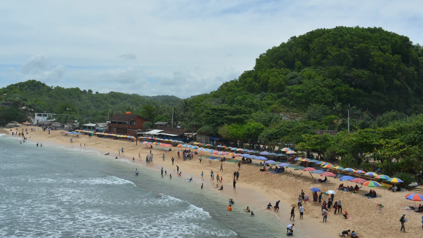 Pantai Indrayanti berpasir putih dengan deretan payung warna-warni dan bangunan warung
