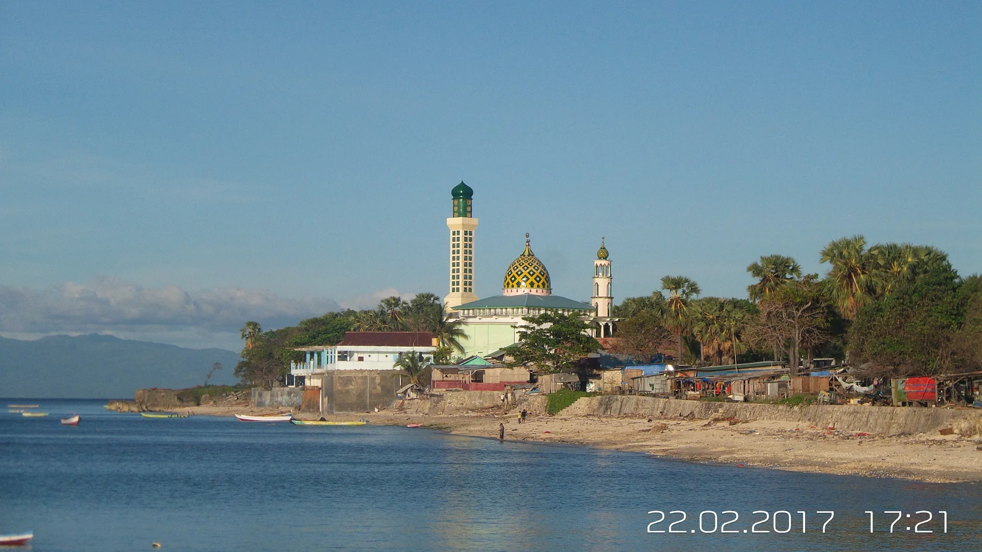 pantai Kota Kupang dengan masjid berkubah kuning dan perahu nelayan pada sore hari