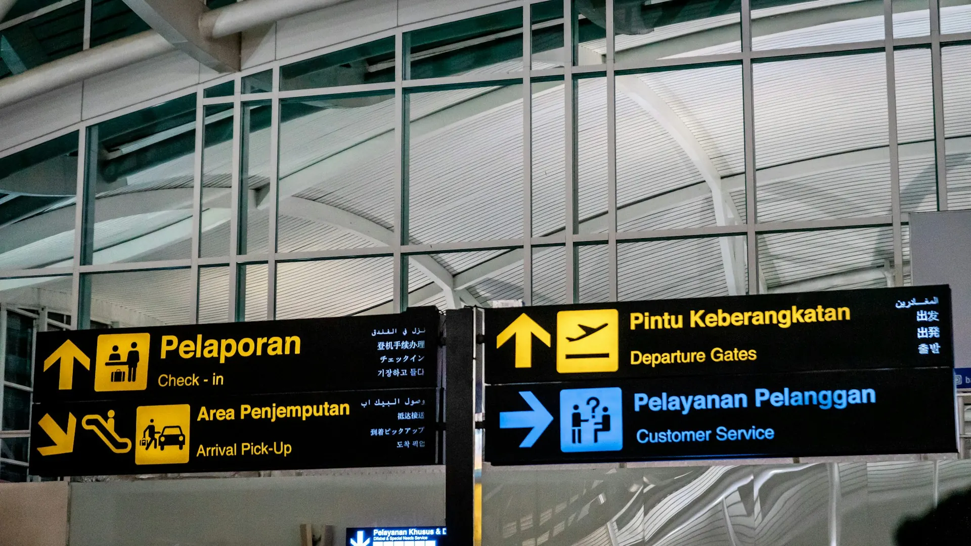 Papan petunjuk arah check-in, pintu keberangkatan, dan pelayanan pelanggan di Bandara I Gusti Ngurah Rai, Bali