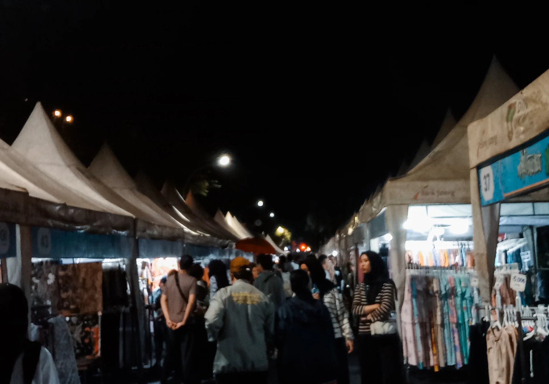 Pengunjung berjalan di antara tenda pedagang pakaian Pasar Malam Ngarsopuro Solo