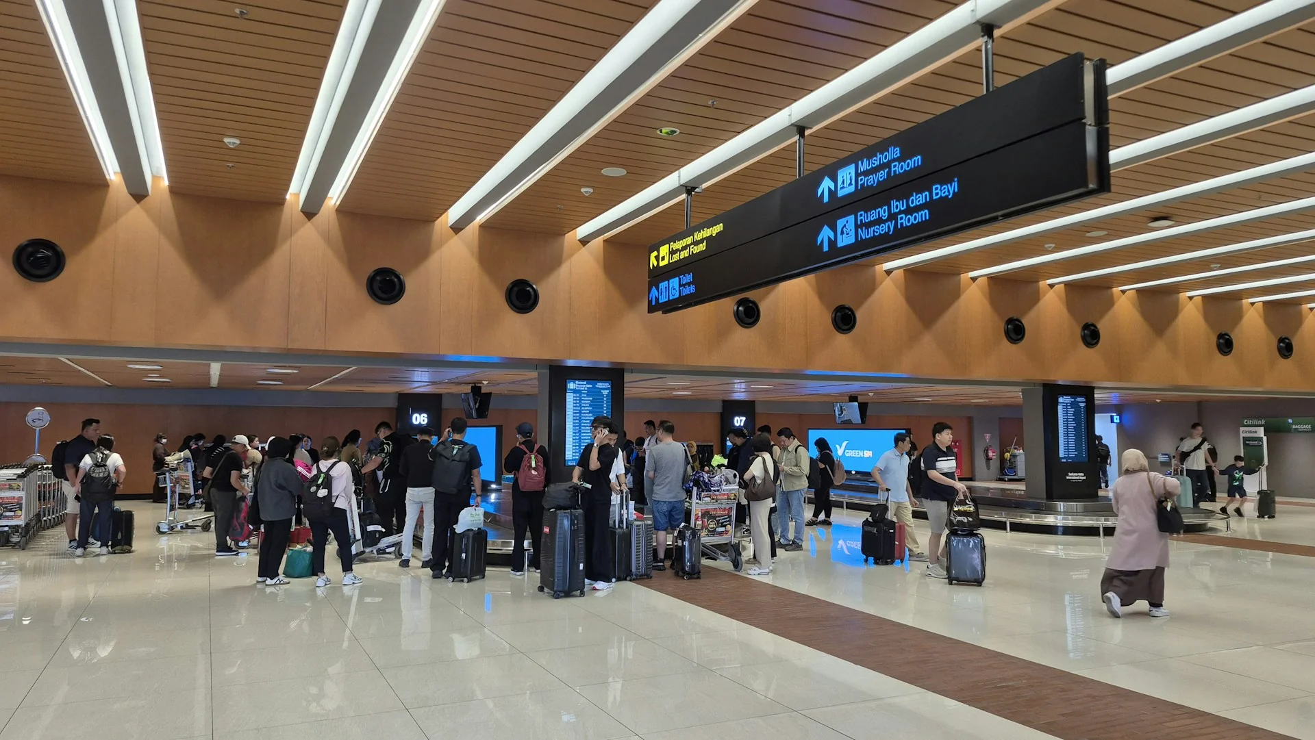 penumpang dengan koper menunggu bagasi di area kedatangan Terminal 1C Bandara Soekarno-Hatta