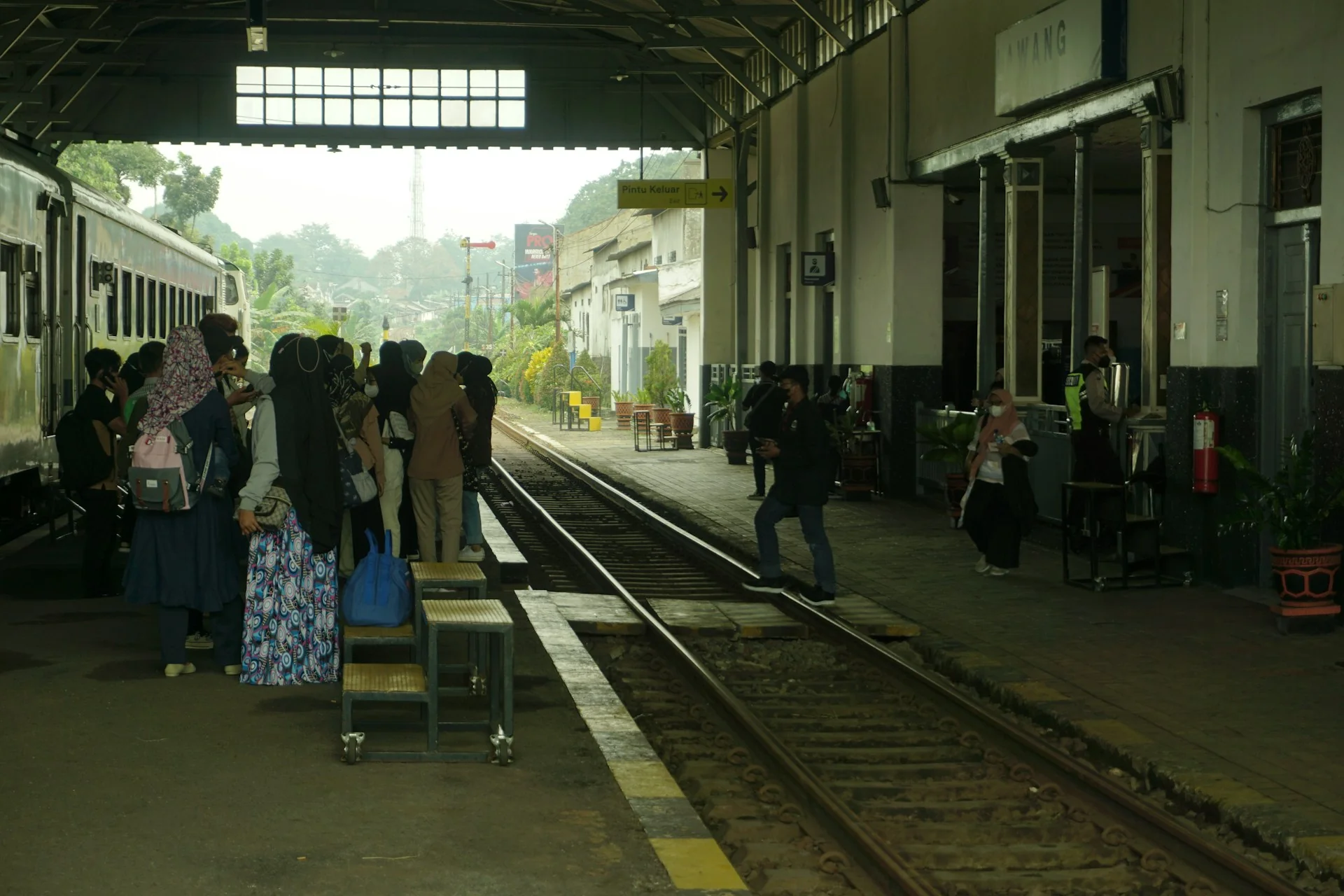 penumpang membawa tas menunggu di peron stasiun di samping rangkaian kereta jarak jauh