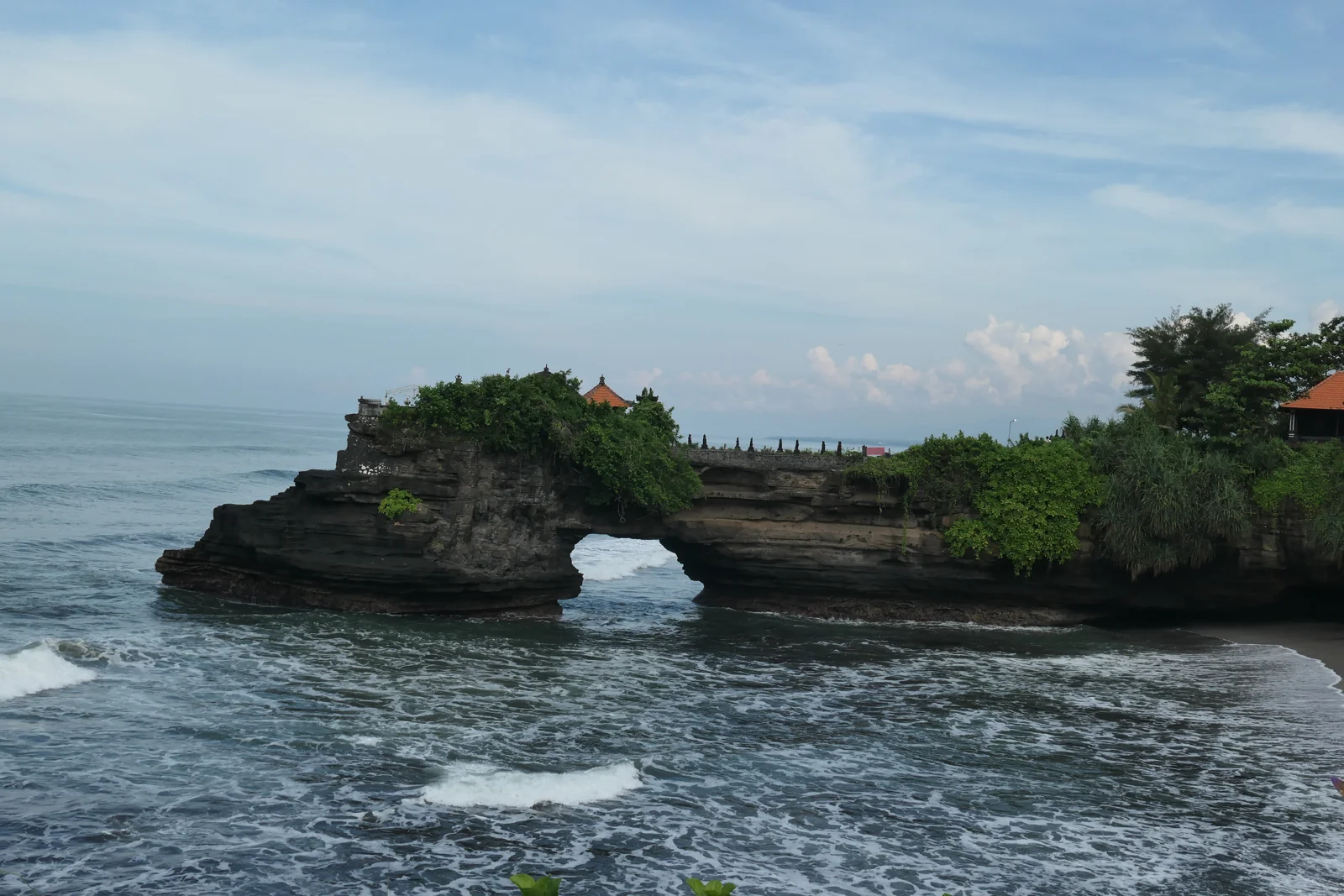 Pura Batu Bolong di atas karang berlubang yang membentuk jembatan alam di tepi laut, kawasan Tanah Lot, Tabanan, Bali