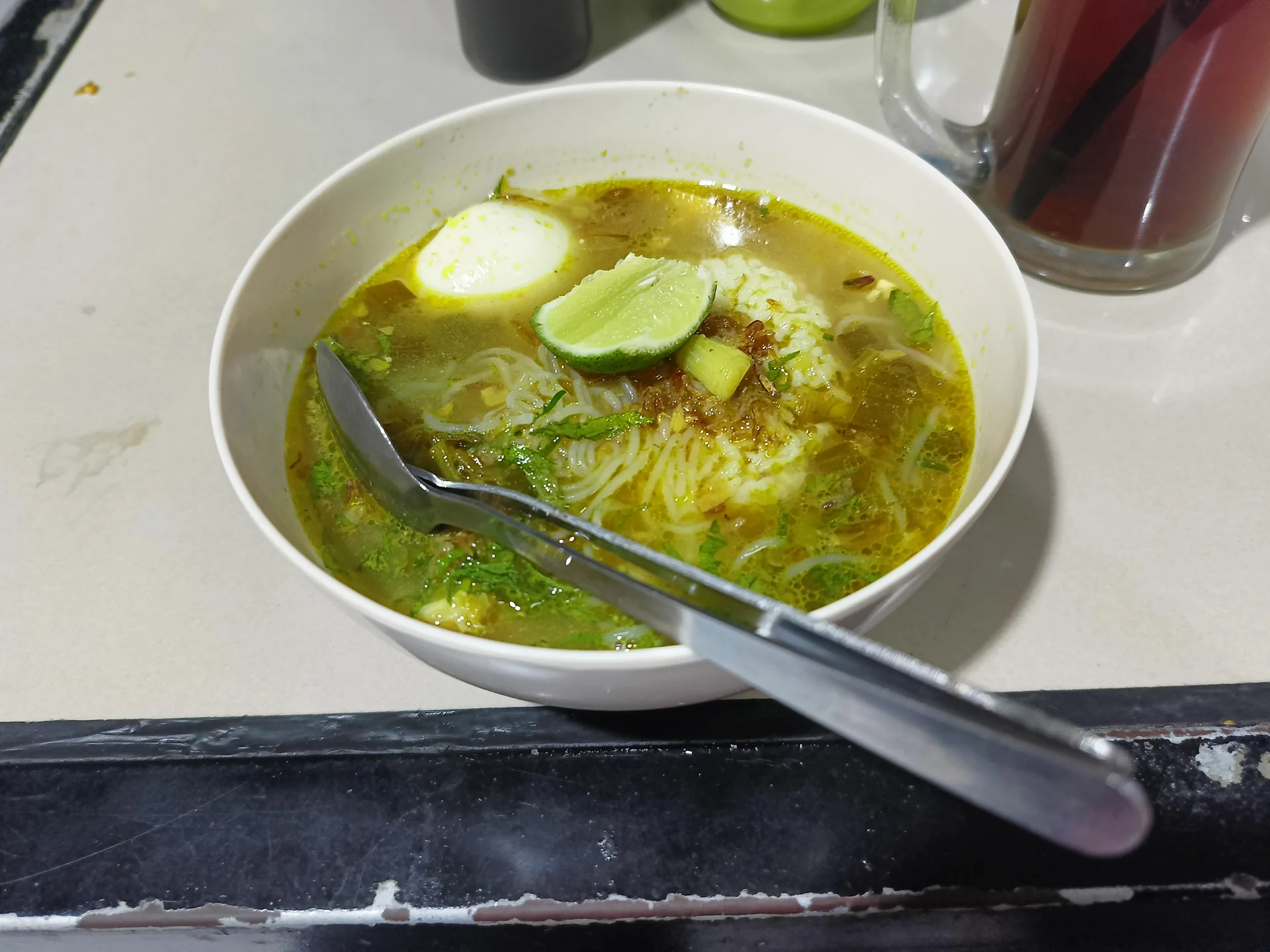 Semangkuk soto ayam berisi nasi, bihun, telur rebus, dan irisan jeruk nipis