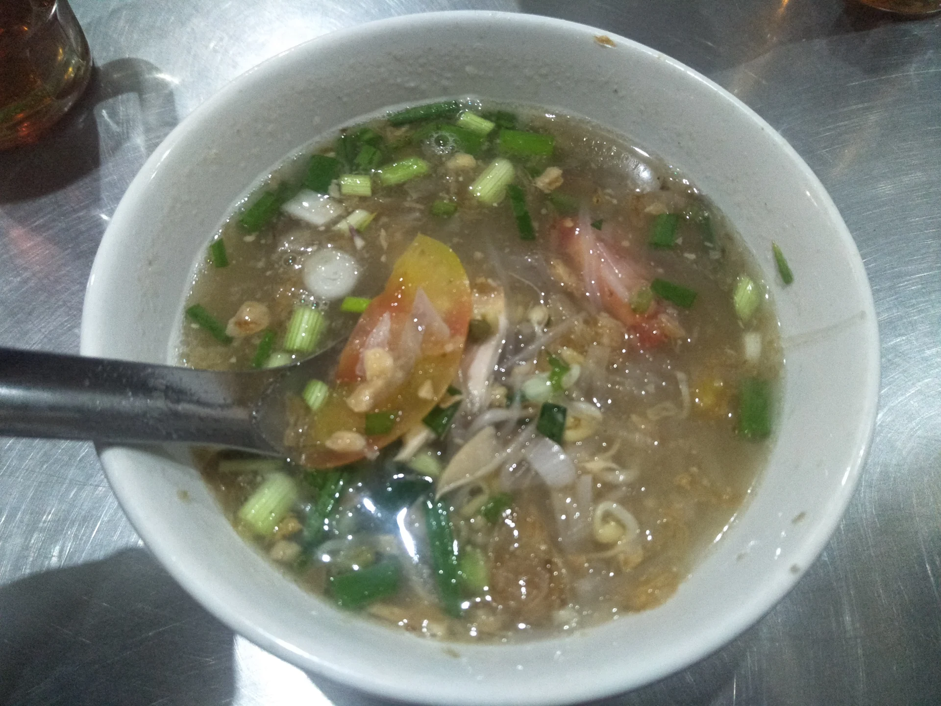 Semangkuk soto Semarang berkuah bening dengan suwiran ayam, tauge, tomat, dan daun bawang