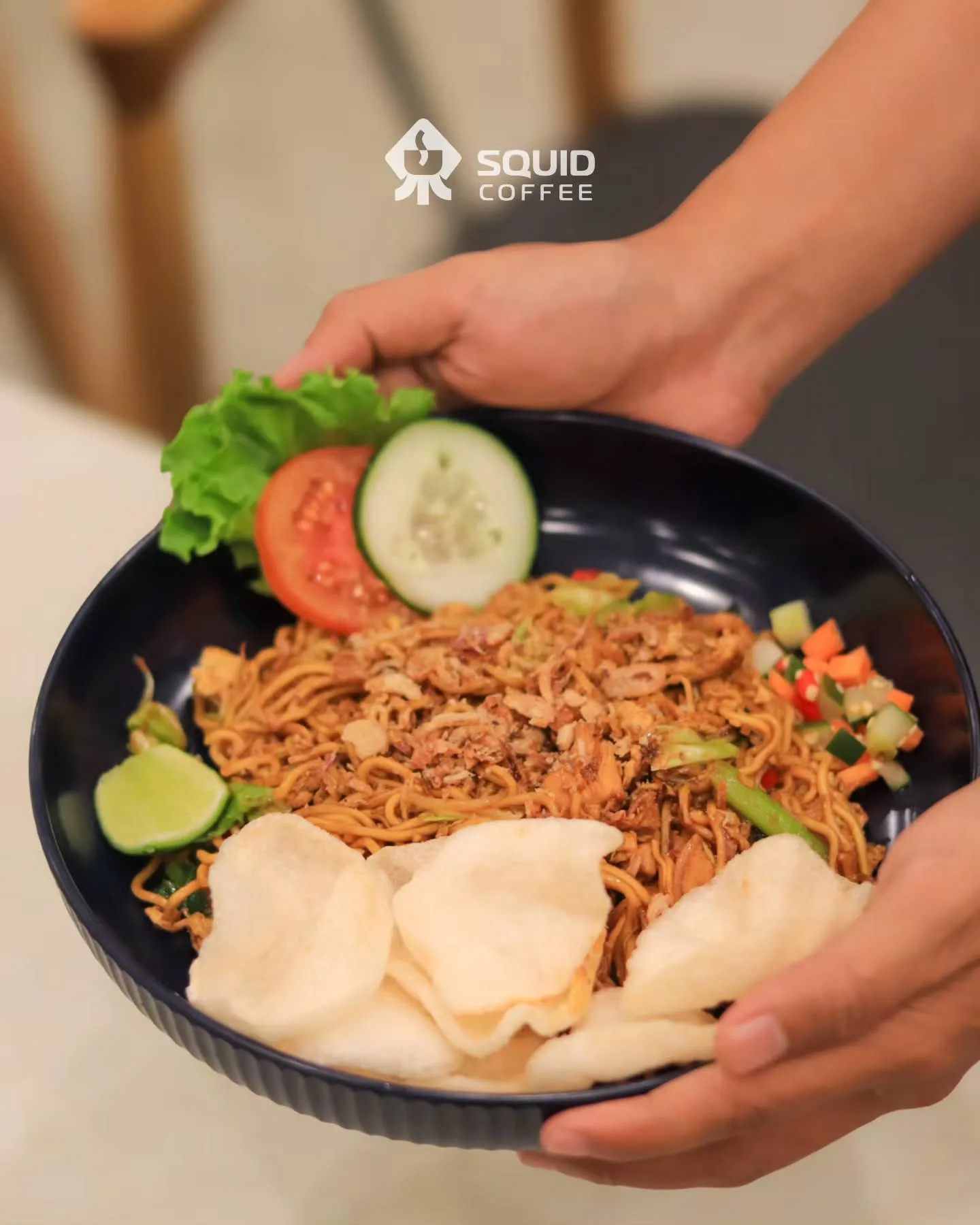 Seporsi mi goreng dengan kerupuk, tomat, mentimun, dan acar di Squid Coffee Makassar