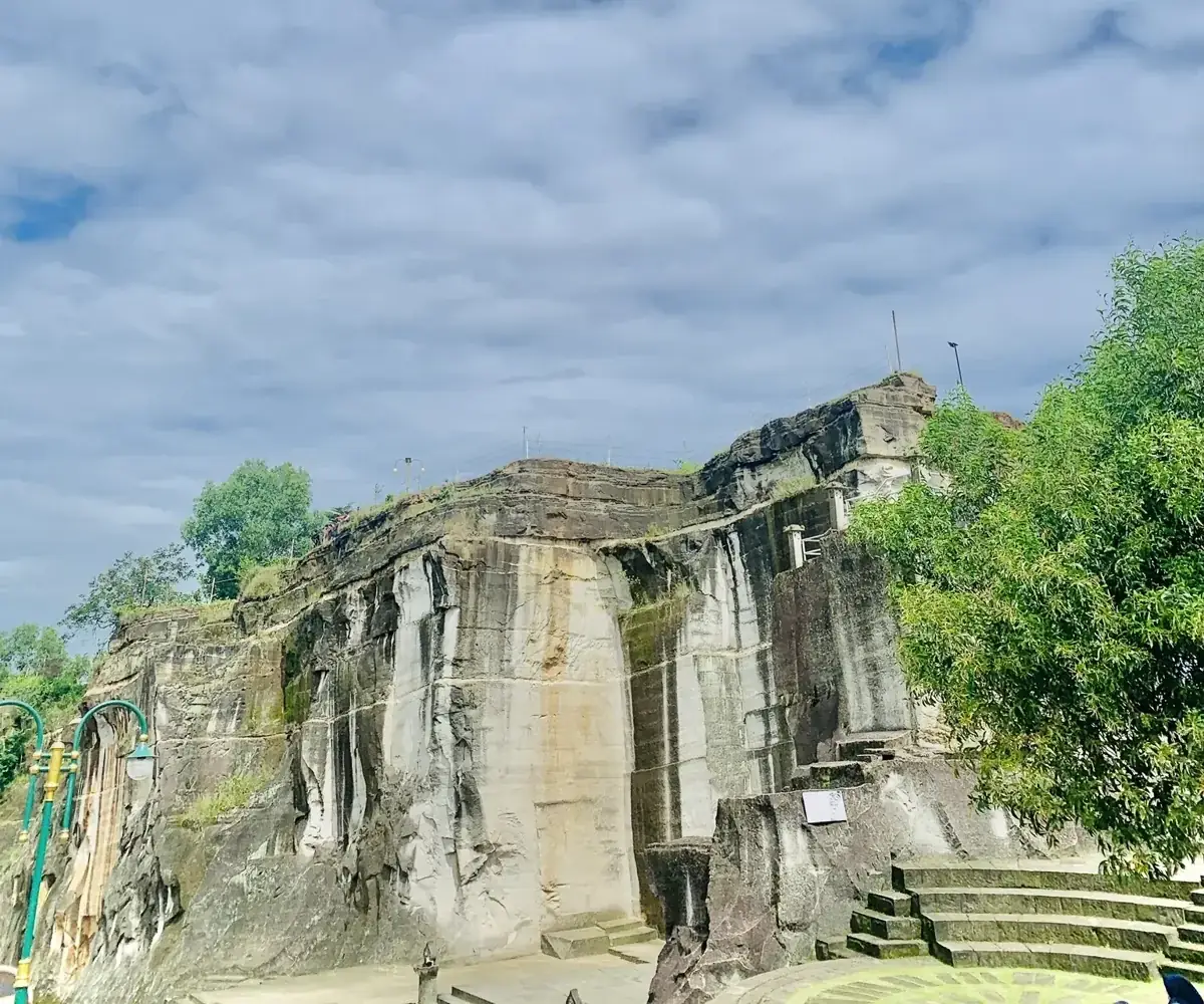 Tebing batu breksi dengan bekas potongan tambang vertikal di bawah langit biru berawan, Tebing Breksi Sleman