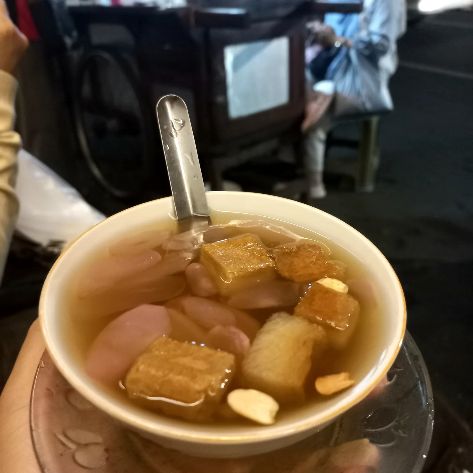 Semangkuk wedang ronde dengan bola ketan, potongan roti, dan kacang
